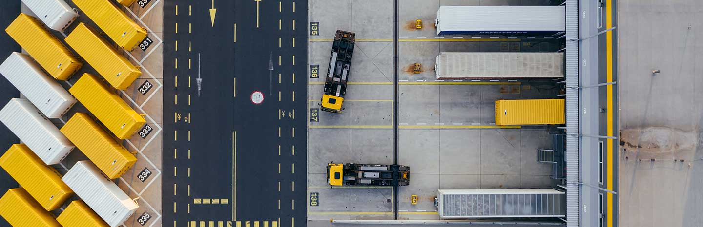 Yellow and black containers and logistics trucks seen from above.