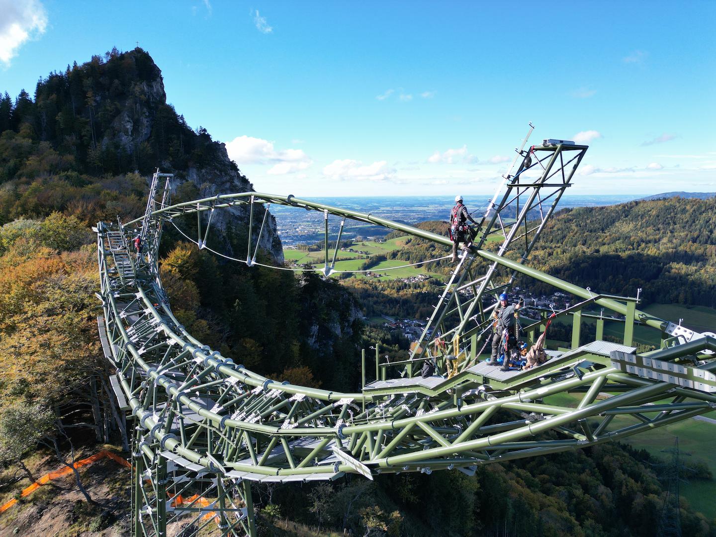 Aerial view of technicians assembling an overhead transmission structure in mountainous terrain