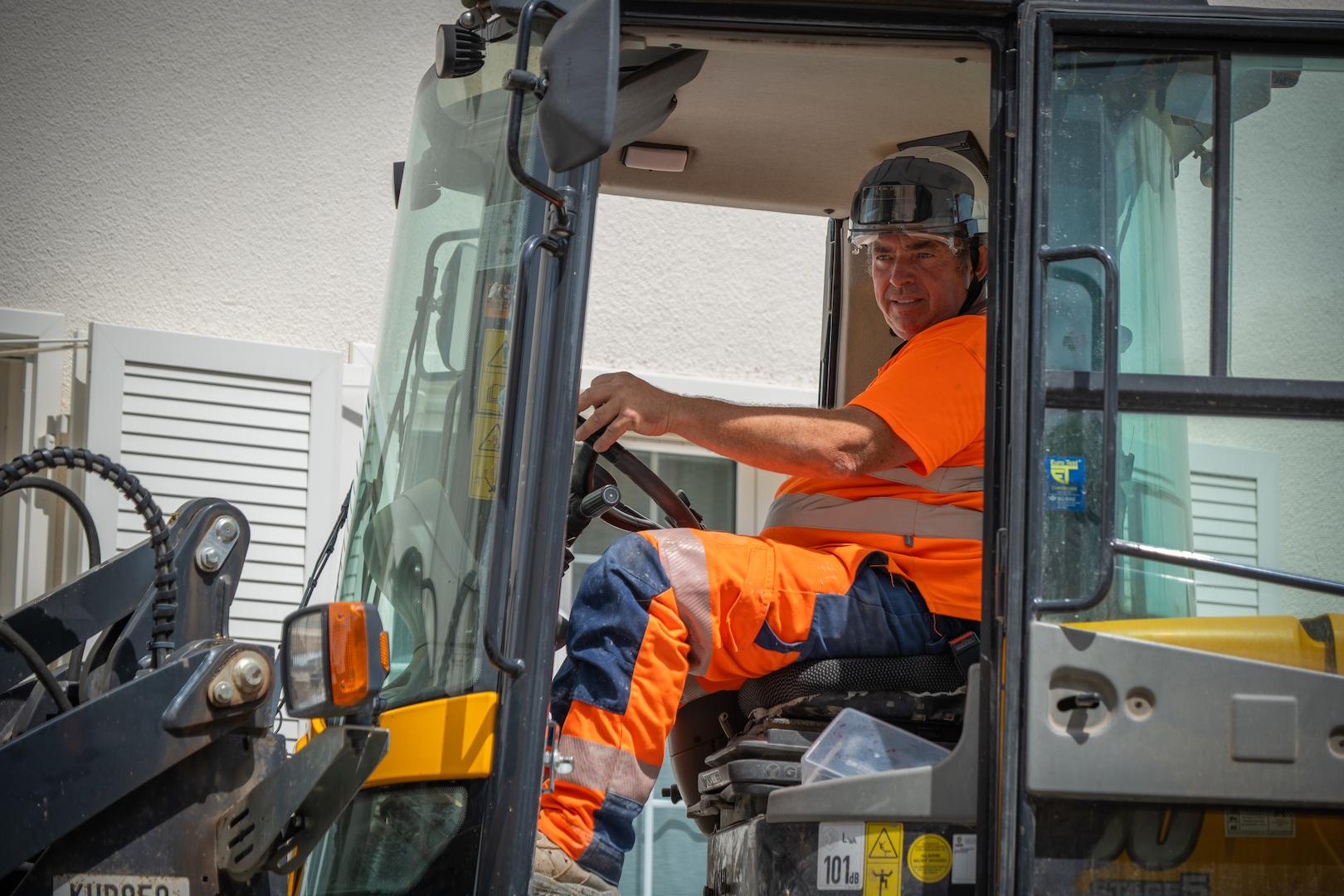 Operator using construction equipment during electricity distribution service works focused on underground network installation