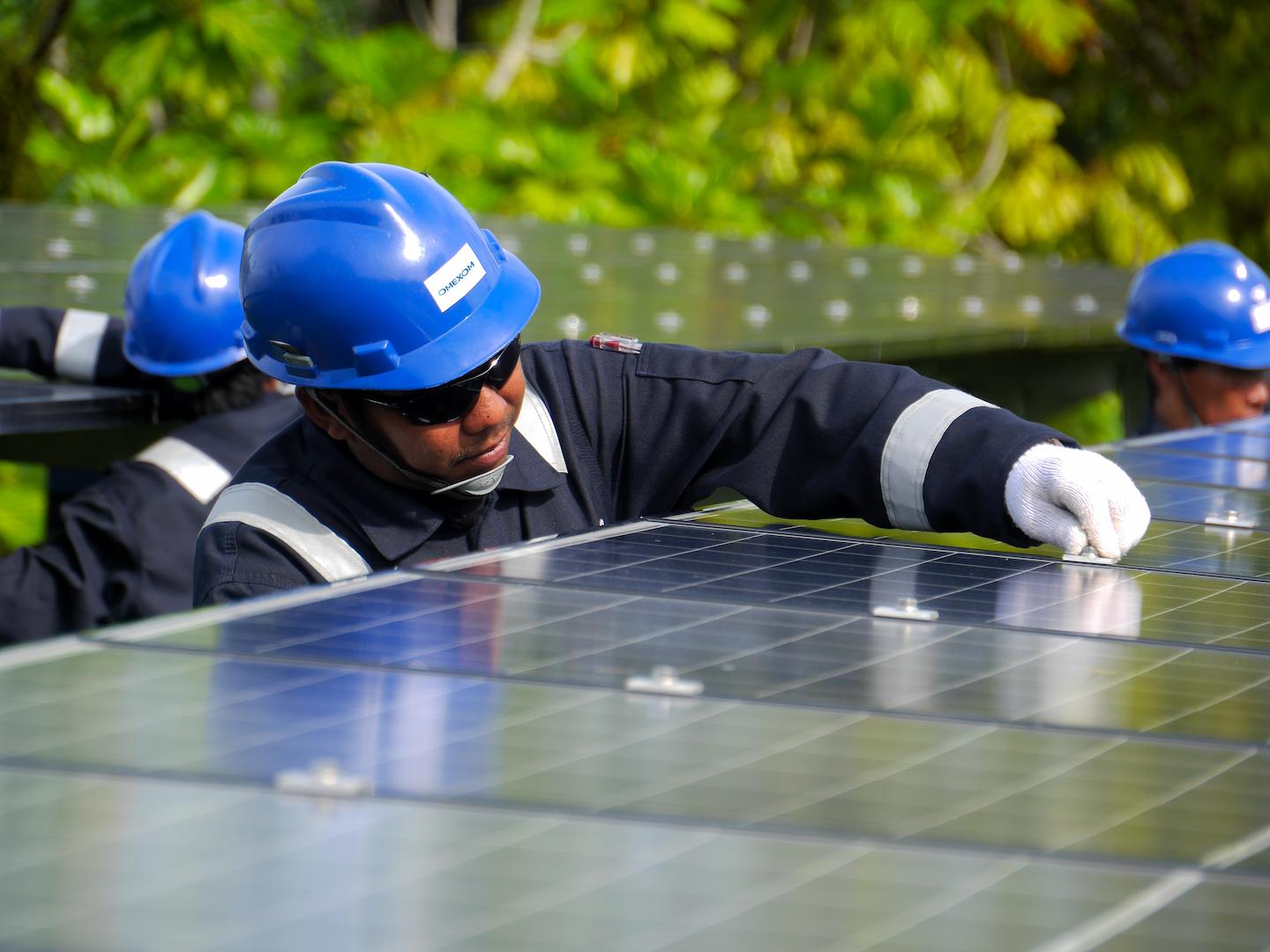 Technicians installing and maintaining solar panels for a renewable energy microgrid, supporting sustainable electricity generation and local energy access