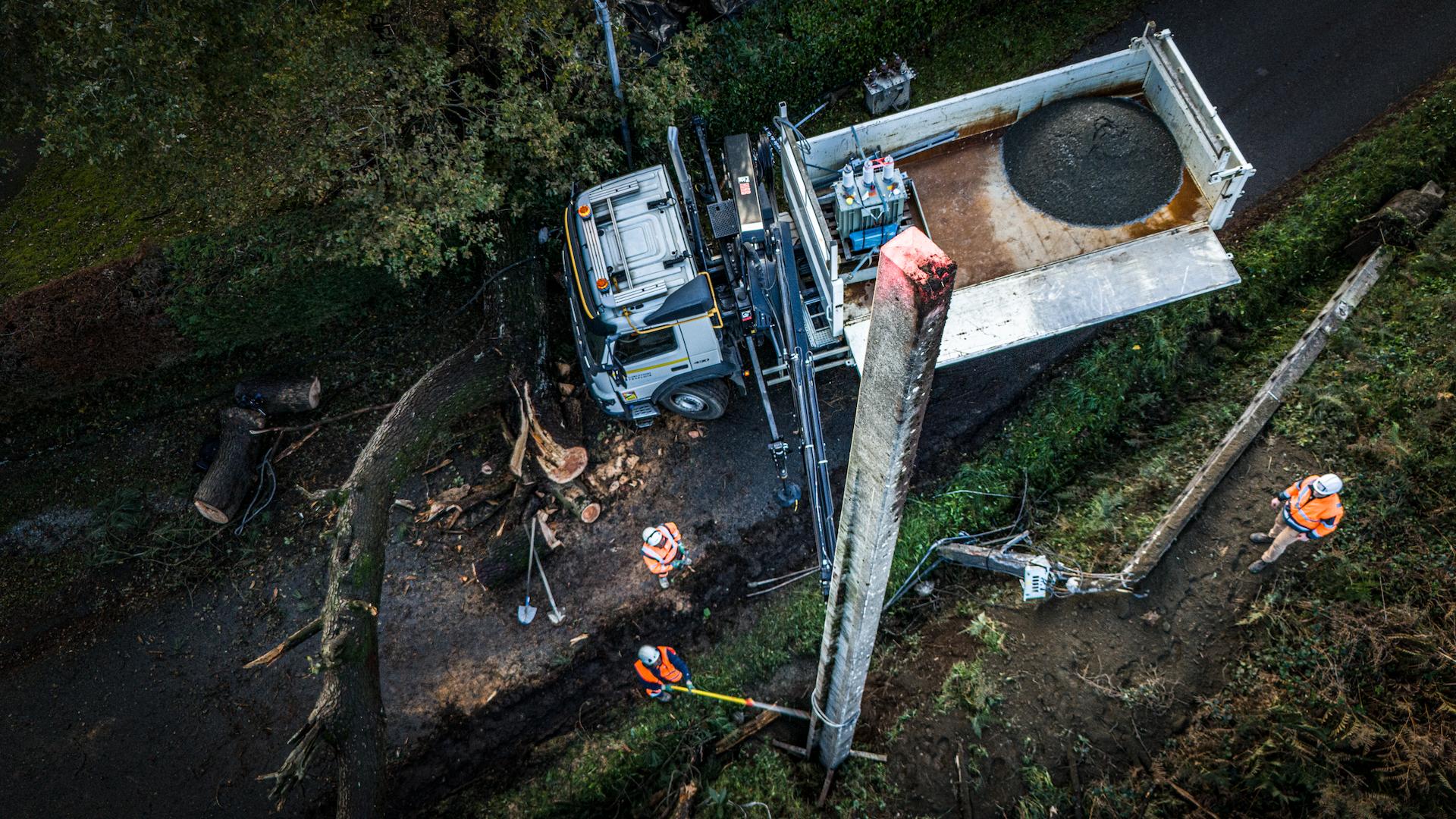Omexom technician performing overhead line installation from an elevated platform, ensuring reliable electricity distribution across open countryside