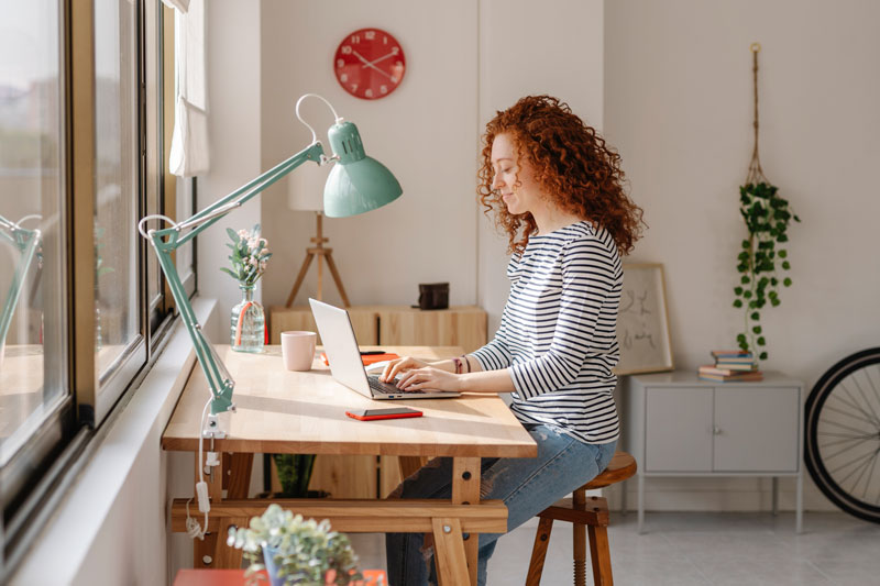 Sicher und schnell von zu Hause arbeiten: Homeoffice Arbeitsplätze mit Citrix Junge Frau sitzt an ihrem Home-Office Schreibtisch und arbeitet.