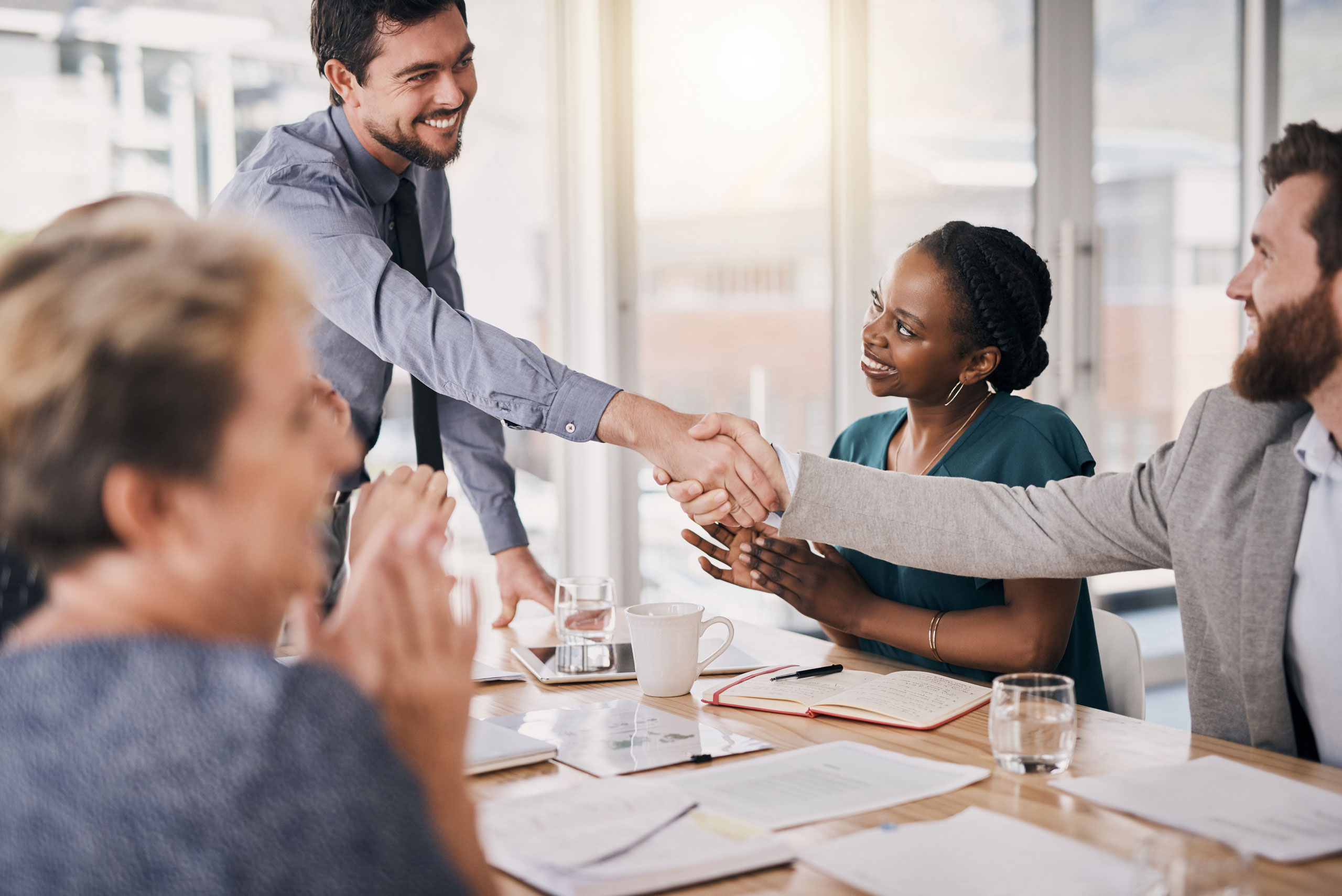 Junge, schick gekleidete Menschen im Meeting schütteln sich die Hand.